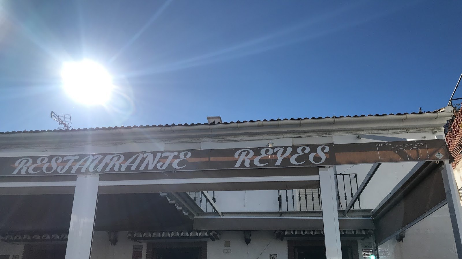 Toldo marrón del Bar Restaurante Reyes con el nombre en letras blancas sobre la terraza